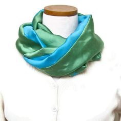 a woman wearing a green and blue scarf on top of a white mannequin