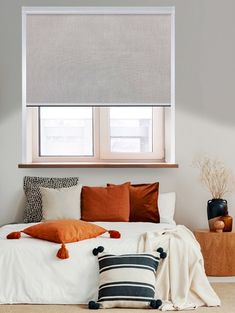 a white bed topped with pillows under a window