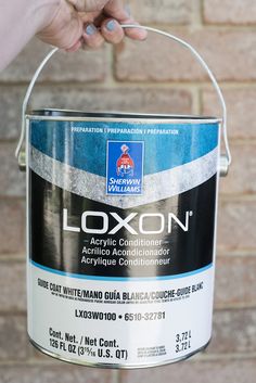 a person holding a paint can in front of a brick wall with the words oxon painted on it