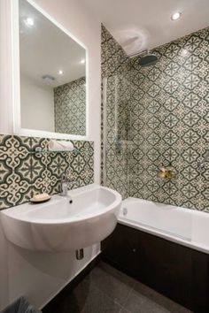 a white sink sitting under a mirror next to a bath tub