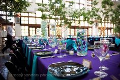 the table is set with purple linens and place settings for guests to sit at