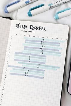 an open notebook with the words sleep tracker written on it next to markers and pens