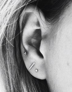 a woman's ear with two piercings on it