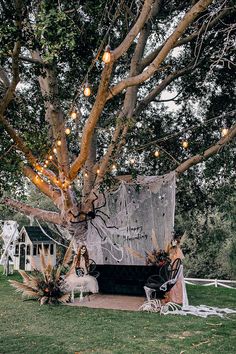 a tree with lights hanging from it's branches in front of a white tent