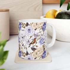 a coffee mug sitting on top of a counter next to some lemons and an avocado