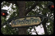 a street sign hanging from the side of a tree next to a traffic light on a pole