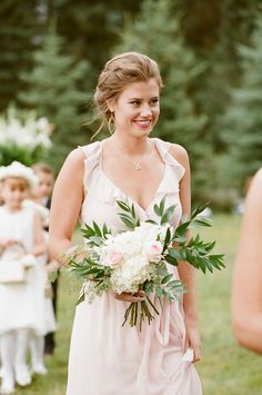 a bride and her flower girl walking down the aisle at their outdoor wedding in summer