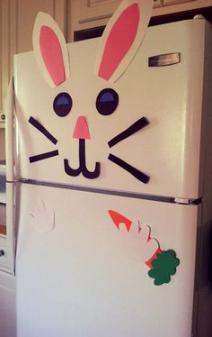 a refrigerator decorated with bunny ears and carrots on the front, in a kitchen