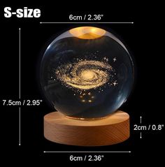 an image of a glass ball with gold stars in it on a wooden base and measurements