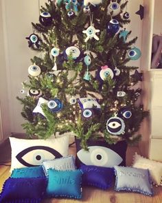 a christmas tree decorated with blue and white ornaments is in front of pillows that have eyes on them