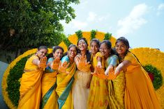 a group of women standing next to each other in front of a flower display holding their hands up