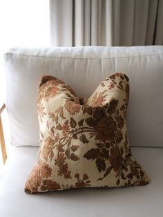 a floral pillow on a white couch in front of a window