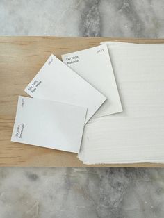 three sheets of white paper sitting on top of a wooden cutting board