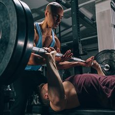 two men doing exercises with barbells in a gym