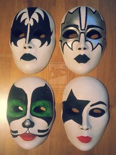 four masks with different designs on them sitting on a wooden table in front of a door