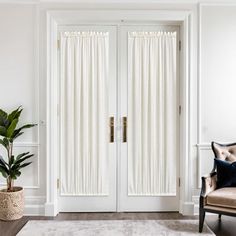 a living room with two white doors and a brown chair in front of the door