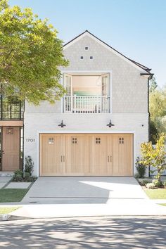 a white house with two garages and trees