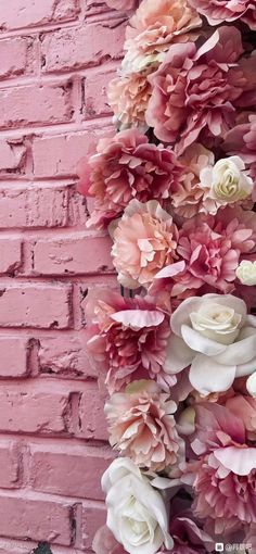 pink and white flowers against a brick wall