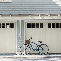 a blue bicycle parked in front of two garage doors