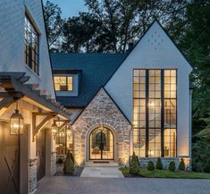 a large brick house with lots of windows and lights on the front door is lit up at night