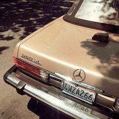 an old mercedes is parked on the side of the road