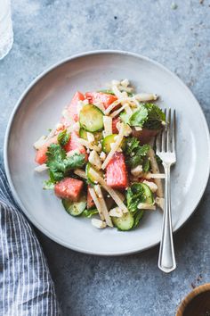 a white plate topped with salad next to a fork