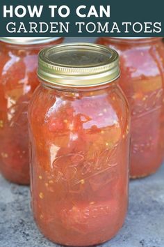 three jars filled with red tomatoes sitting on top of a cement ground next to each other