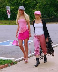 two young women walking down the street in pink outfits and matching hats with one another