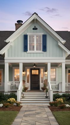 a white house with blue shutters and steps leading to the front door at dusk