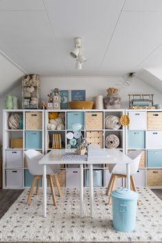 a white table and chairs in a room with lots of storage containers on the wall