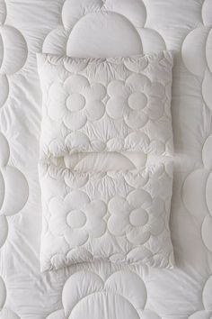 two pillows are placed on top of a white quilted comforter and pillowcase