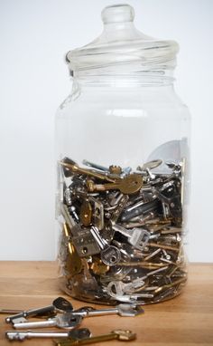 a jar filled with lots of keys on top of a wooden table