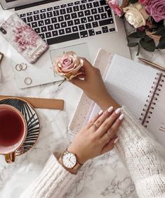 a woman's hand on her wrist next to a laptop computer and coffee cup