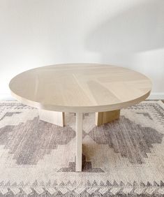 a round wooden table sitting on top of a rug