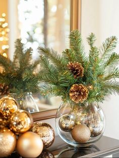 a vase filled with pine cones and ornaments on top of a table next to a mirror