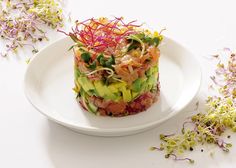 a white plate topped with a salad covered in veggies and sprouts