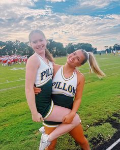 two cheerleaders hugging each other on the field