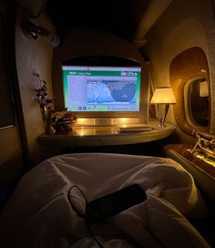 an airplane cabin with a bed, desk and computer monitor on the wall in front of it