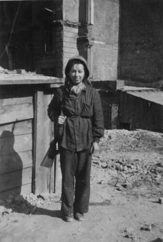 an old black and white photo of a woman standing in front of a building