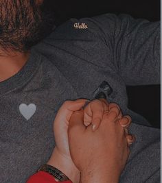 a man is holding the hand of another person who is wearing a heart shaped pin