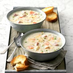 two bowls of soup with bread on the side