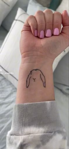 a woman's arm with a small tattoo on the wrist and an outline of a bunny