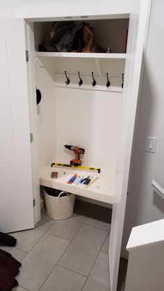 a white closet with some tools on the floor and other items in front of it