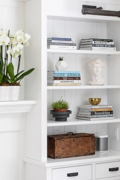 a white bookcase filled with books and flowers