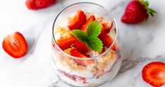 strawberries and yogurt in a glass on a marble table with mint leaves