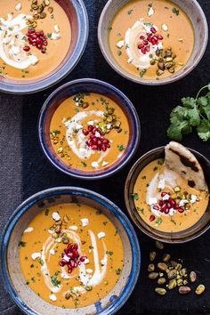 four bowls filled with soup and garnished with pomegranates