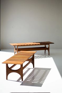 two wooden benches sitting next to each other on top of a white floor in front of a wall