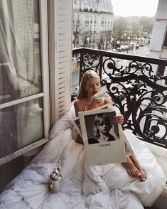 a woman sitting on a bed holding up a sign that says clinkle in front of her face