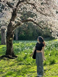 a woman standing in front of a tree with white flowers