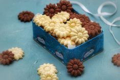 there are some cookies in the shape of flowers on this blue tablecloth with white ribbon